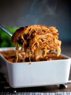 Steaming hot rakott kaposzta, Hungarian sauerkraut casserole being removed from a bowl.