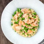 Overhead salmon risotto with green peas and fennel seeds.