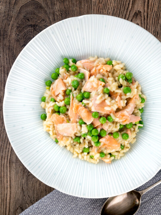 Overhead salmon risotto with green peas and fennel seeds.