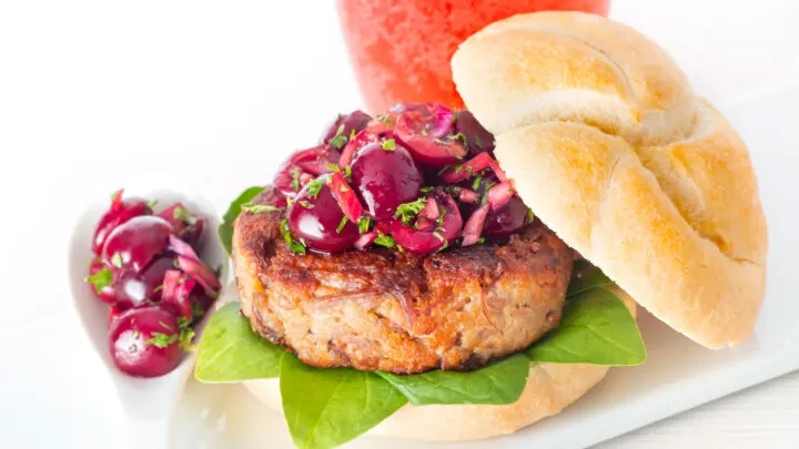 Shredded duck burgers topped with cherry salsa on a burger bun.