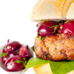 Shredded duck burgers topped with cherry salsa on a burger bun.