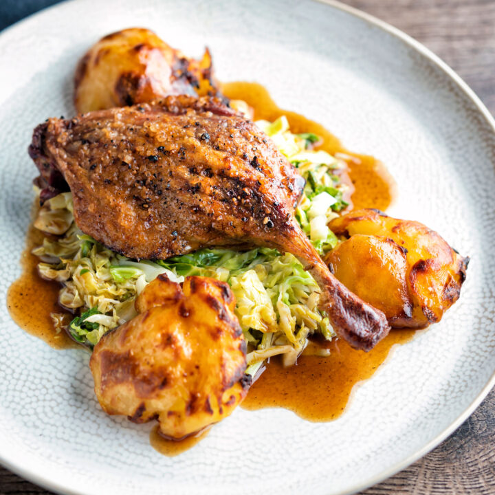 Slow roast duck legs served on cabbage with roast potatoes and balsamic gravy.