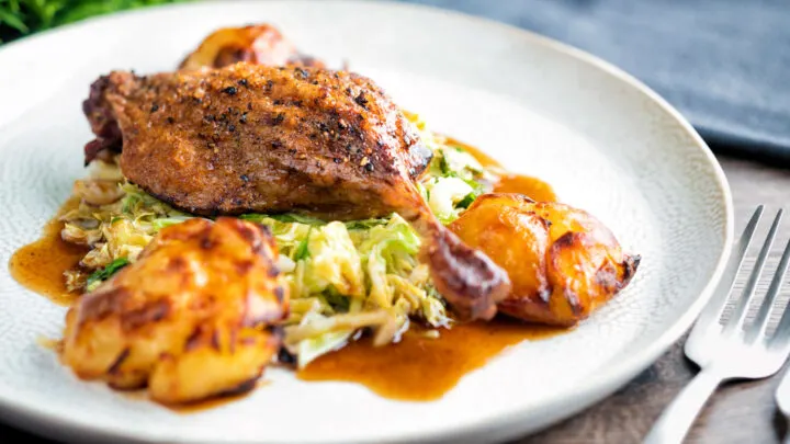 Slow roast duck legs served on cabbage with roast potatoes and balsamic gravy.