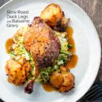 Overhead slow roast duck leg with balsamic gravy, cabbage and roast potatoes featuring a title overlay.