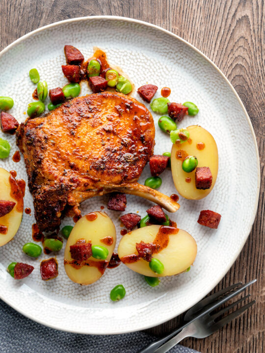 Overhead Spanish pork chops with chorizo sausage, broad beans and potatoes.