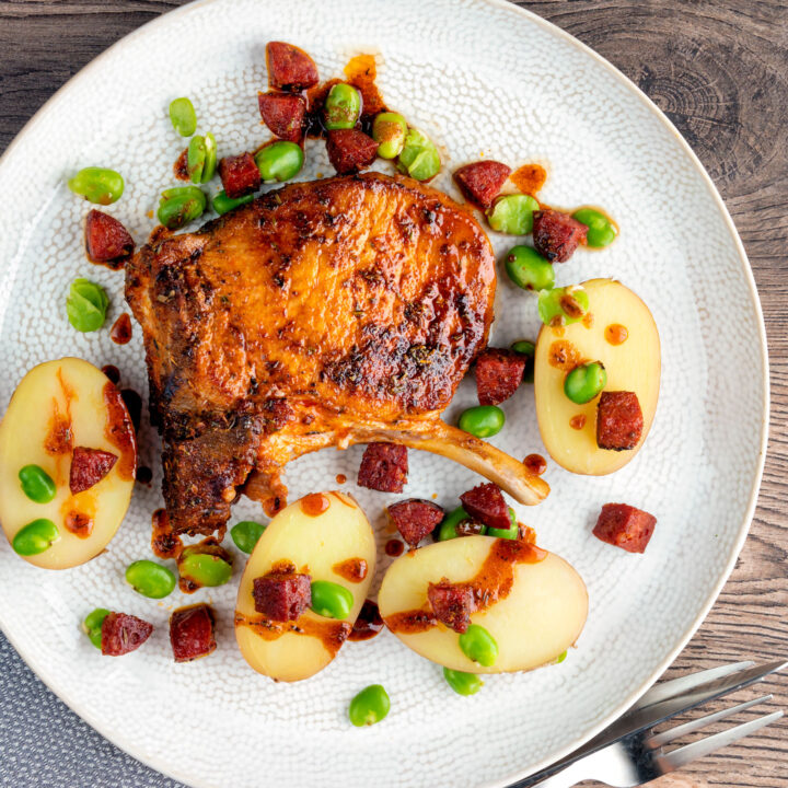 Spanish pork chops with chorizo sausage, broad beans and potatoes with paprika oil.