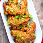 Overhead sticky spicy Thai inspired chicken wings with green onion.
