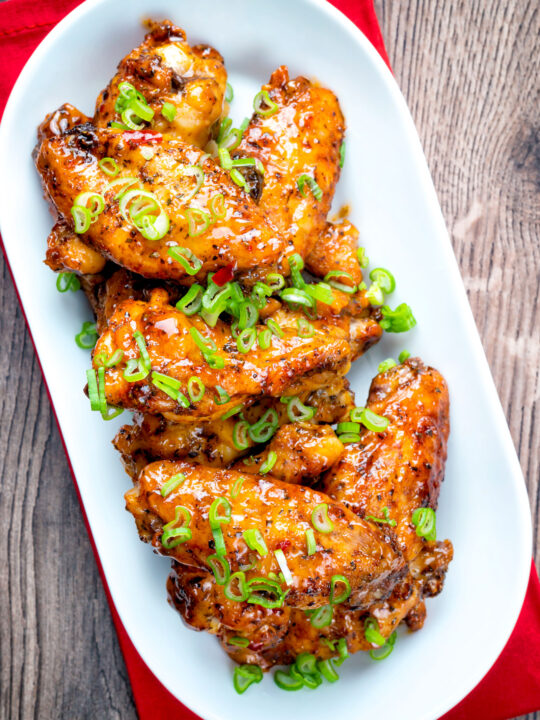 Overhead sticky spicy Thai inspired chicken wings with green onion.
