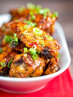 Close up sticky spicy Thai inspired chicken wings with green onion.