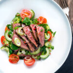 Overhead Thai beef salad with rare beef, tomatoes, mint, chilli and cucumber.
