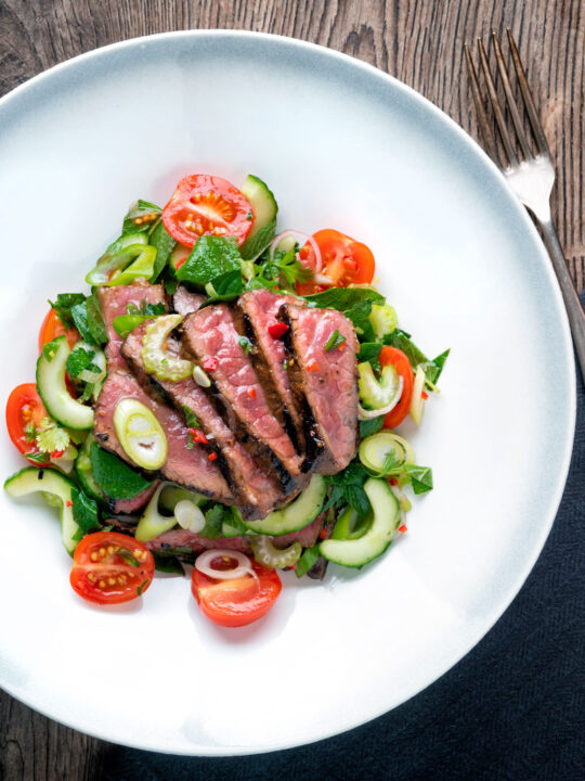 Overhead Thai beef salad with rare beef, tomatoes, mint, chilli and cucumber.