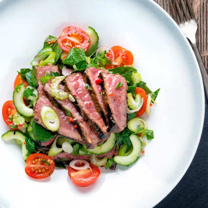 Overhead Thai beef salad with rare beef, tomatoes, mint, chilli, shallot, celery and cucumber.