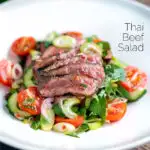 Thai beef salad with rare beef, tomatoes, mint, chilli, shallot, celery and cucumber featuring a title overlay.