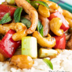 Close up Thai cashew chicken stir fry served on steamed rice featuring a title overlay.