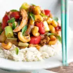 Thai cashew chicken stir fry served on steamed rice featuring a title overlay.