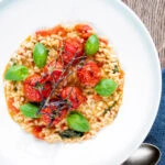 Overhead tomato risotto with basil and roasted tomatoes.