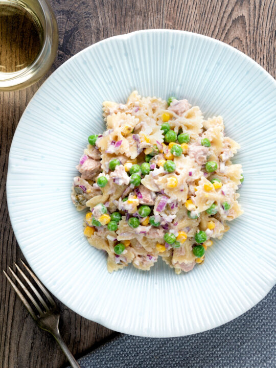 Overhead tuna pasta salad with peas, corn and red oniion.