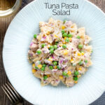 Overhead tuna pasta salad with peas, corn and red onion featuring a title overlay.