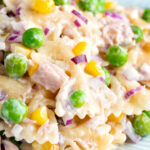Close up tuna pasta salad with peas, corn and red onion.