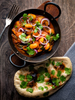 Overhead Indian butter bean curry served with a naan bread.