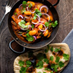 Overhead Indian butter bean curry served with a naan bread featuring a title overlay.