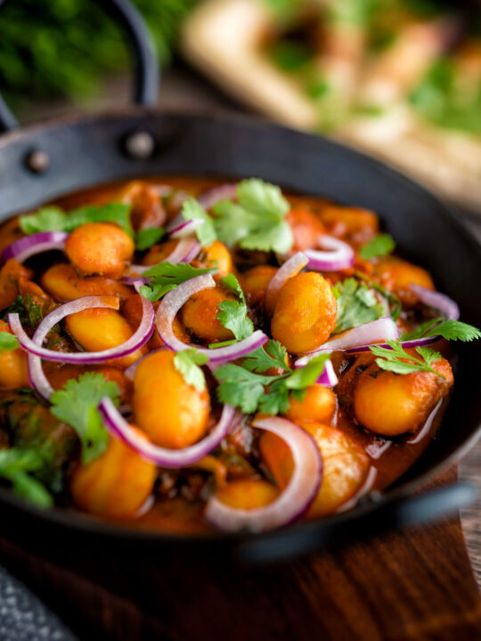 Indian vegan butter bean curry served with coriander and red onion.