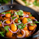 Indian vegan butter bean curry served with coriander and red onion featuring a title overlay.