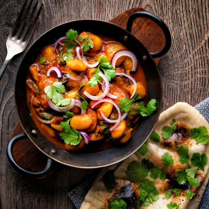 Indian vegan butter bean curry served with coriander, red onion and a naan bread.