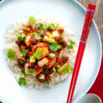 Overhead crispy fried tofu with a spicy Vietnamese tomato sauce featuring a title overlay.