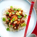 Overhead crispy fried tofu with a spicy Vietnamese tomato sauce featuring a title overlay.