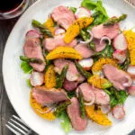 Overhead duck breast salad with roasted radish and asparagus with orange segments.