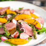 Duck breast salad with rocket, roasted radish and asparagus with orange segments.