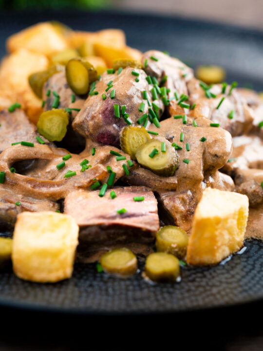 Beef and mushroom stroganoff served with fried potatoes and pickles.