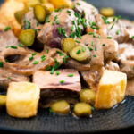 Beef and mushroom stroganoff served with fried potatoes and pickles featuring a title overlay.