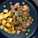 Overhead beef and mushroom stroganoff served with fried potatoes and pickles.
