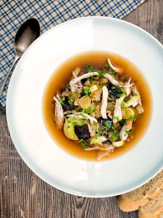 Overhead Scottish cock a leekie soup, chicken and leek soup in a white bowl.