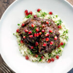 Overhead Iranian fesenjan chicken stew with pomegranate and herbed rice.