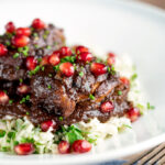 Iranian fesenjan chicken thigh stew with pomegranate served on herbed rice.