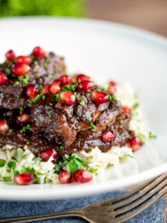 Iranian fesenjan chicken thigh stew with pomegranate served on herbed rice.