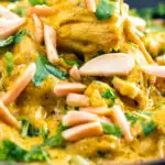 Close up chicken korma curry garnished with coriander and almonds featuring a title overlay.