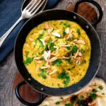 Overhead chicken korma curry garnished with coriander and almonds.
