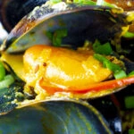 Close up Indian curry mussels in a coconut milk sauce.