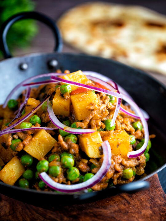Minced beef curry with peas and potatoes served with a naan bread.