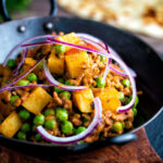 Minced beef curry with peas and potatoes served with a naan bread featuring a title overlay.