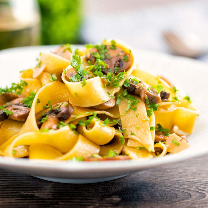 Mushroom pappardelle with balsamic vinegar served in a white bowl with parsley.