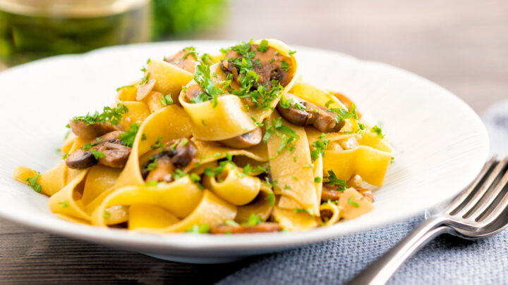 Mushroom pappardelle with balsamic vinegar served in a white bowl with parsley.