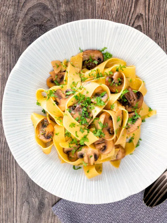 Garlic mushroom pappardelle with balsamic vinegar served in a white bowl.