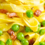 Close up tagliatelle carbonara with peas and bacon.