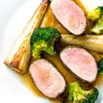 Overhead roast pork fillet served with apple puree, roast parsnips and broccoli.