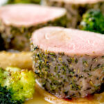 Close up roast pork fillet served with apple puree, roast parsnips and broccoli.